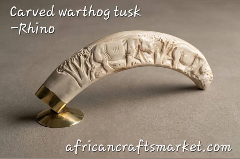 Carved Warthog Tusk - Rhino Exquisite hand-carved genuine warthog tusk sculpture featuring an intricate relief carving of an African rhinoceros in the wild