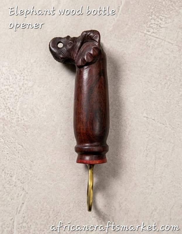 Elephant wood botte opener A handcrafted African wooden bottle opener beautifully carved into the shape of an elephant with an upright trunk, featuring detailed hand-painted touches and a sturdy integrated metal opener