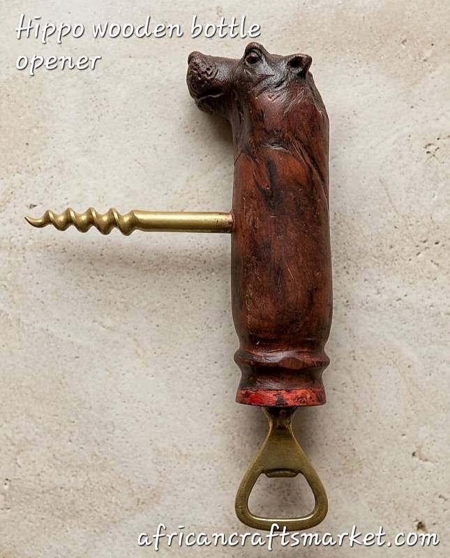 Hippo wood bottle opener A handcrafted African wooden bottle opener carved into the smooth, heavy shape of a hippopotamus, featuring a durable metal opener mechanism integrated into the base
